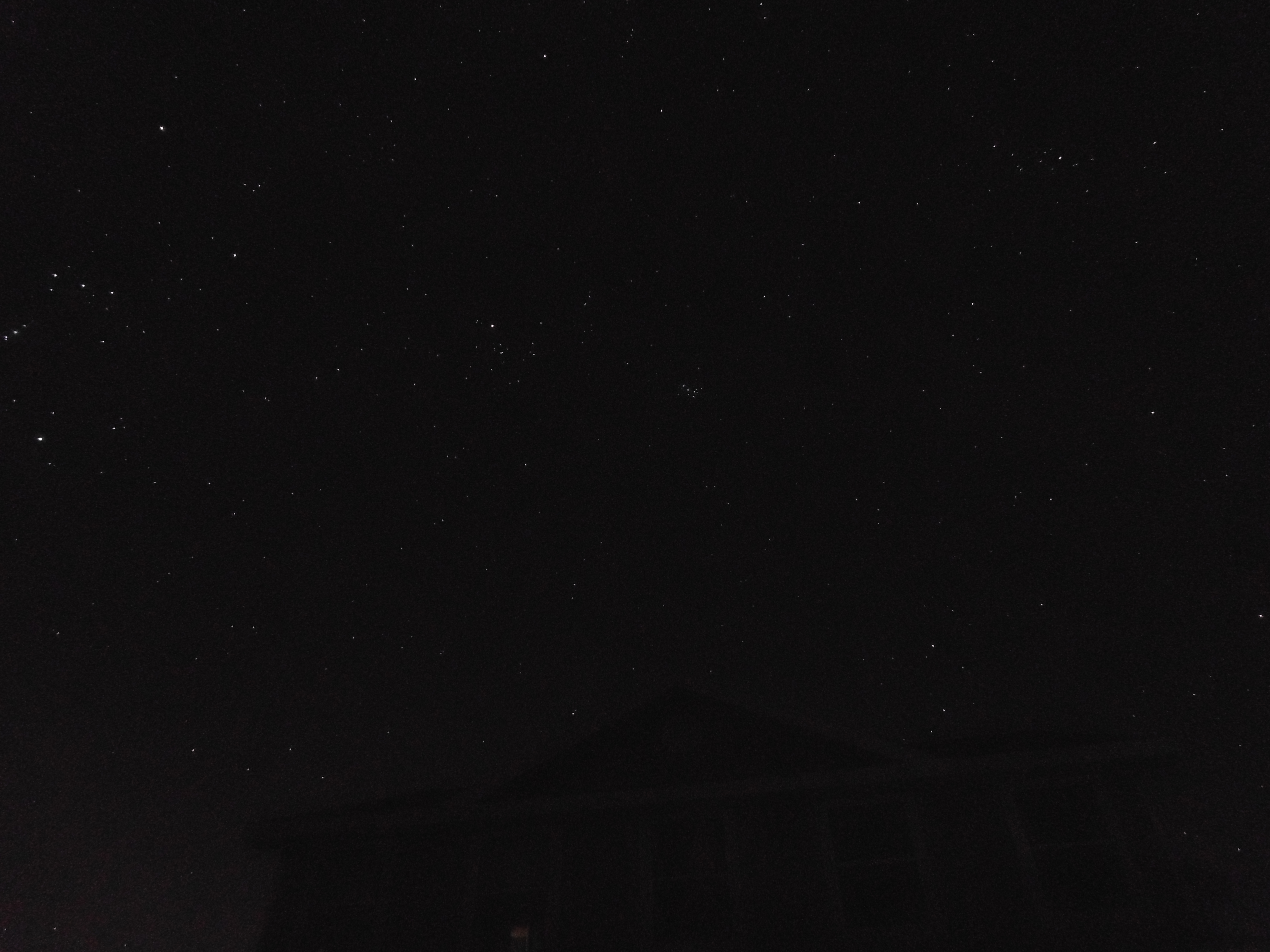 A star-filled night sky above a darkened house