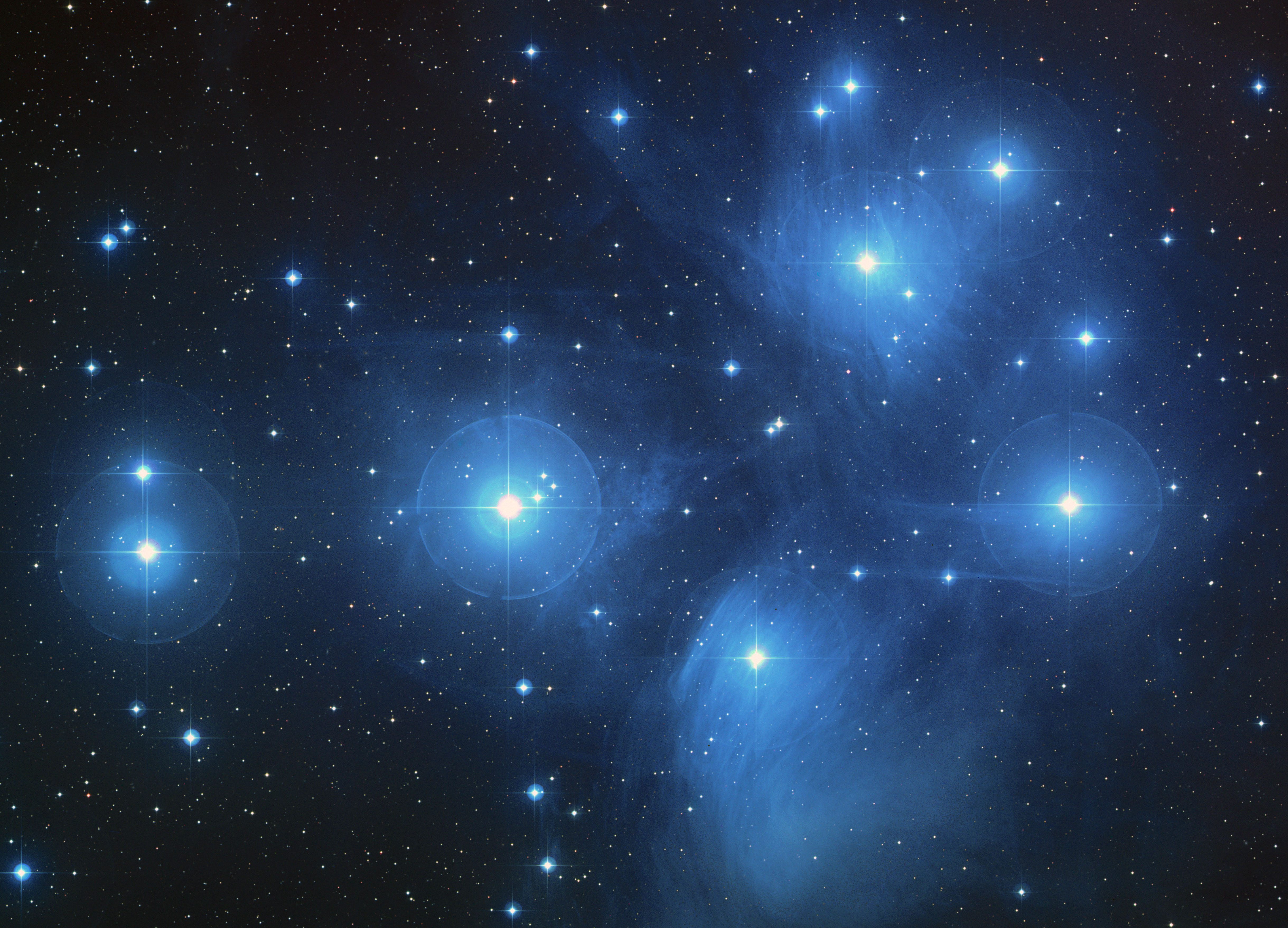 The Pleiades star cluster glowing blue against deep space
